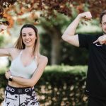 A cheerful couple posing outdoors in activewear, showcasing fitness and well-being.