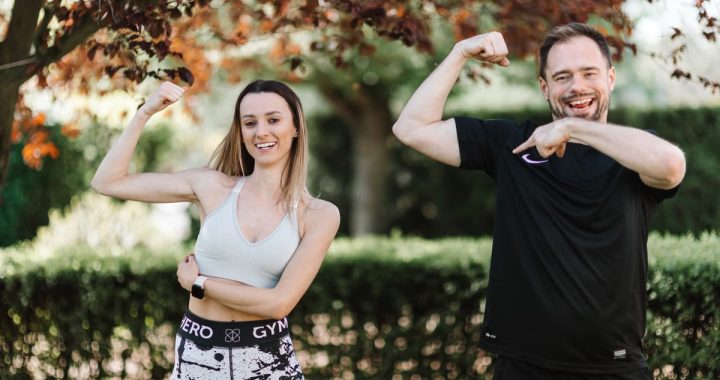 A cheerful couple posing outdoors in activewear, showcasing fitness and well-being.